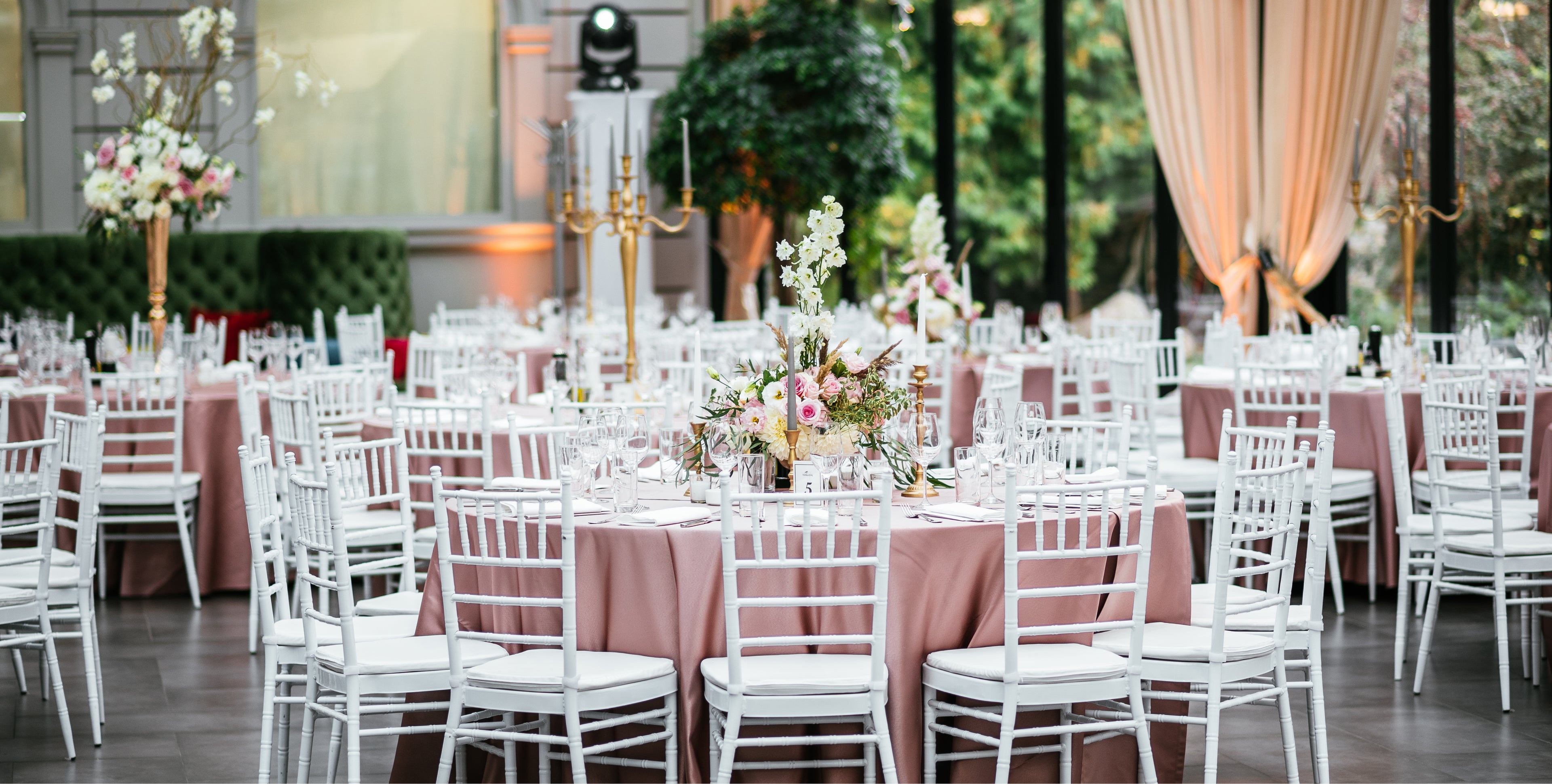 Weiß lackierte Chiavari-Stühle und runde Bankett-Tische mit roséfarbenen Tischdecken – stilvolle Mietmöbel für Hochzeiten und Events in Schleswig-Holstein