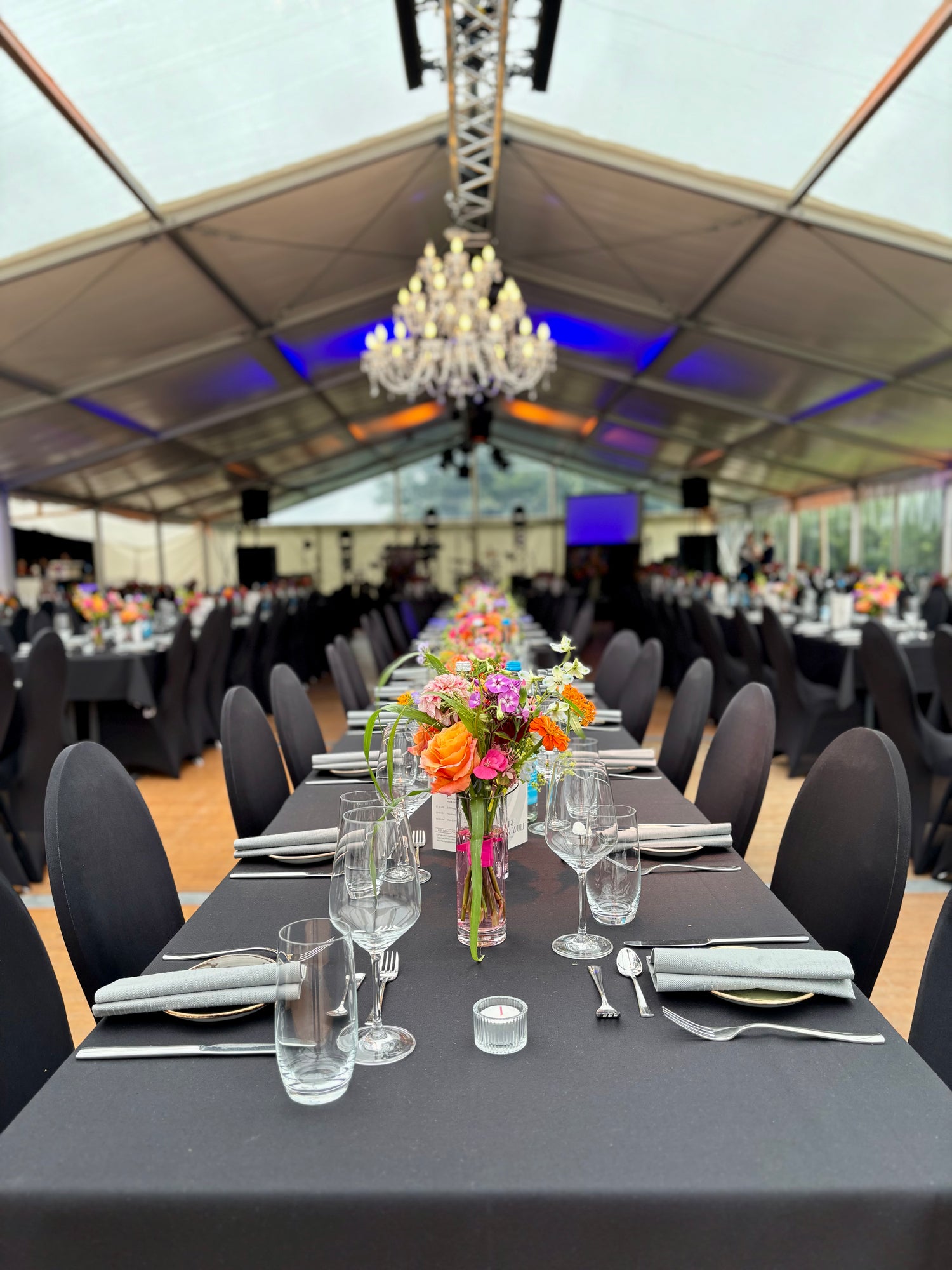 Elegante Festtafel mit schwarzer Tischwäsche, Kronleuchter, komplett eingedeckt und gepolsterte schwarze Stühle bei Business-Event Denker & Wulff