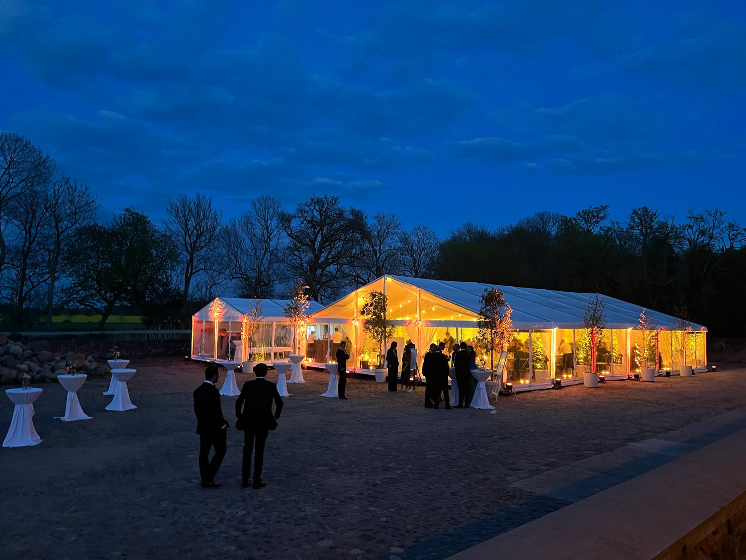 Beleuchtetes Hochzeitszelt bei Nacht mit exklusivem Eventmobiliar und stimmungsvoller Atmosphäre, aufgebaut von Schwartz Veranstaltungstechnik.