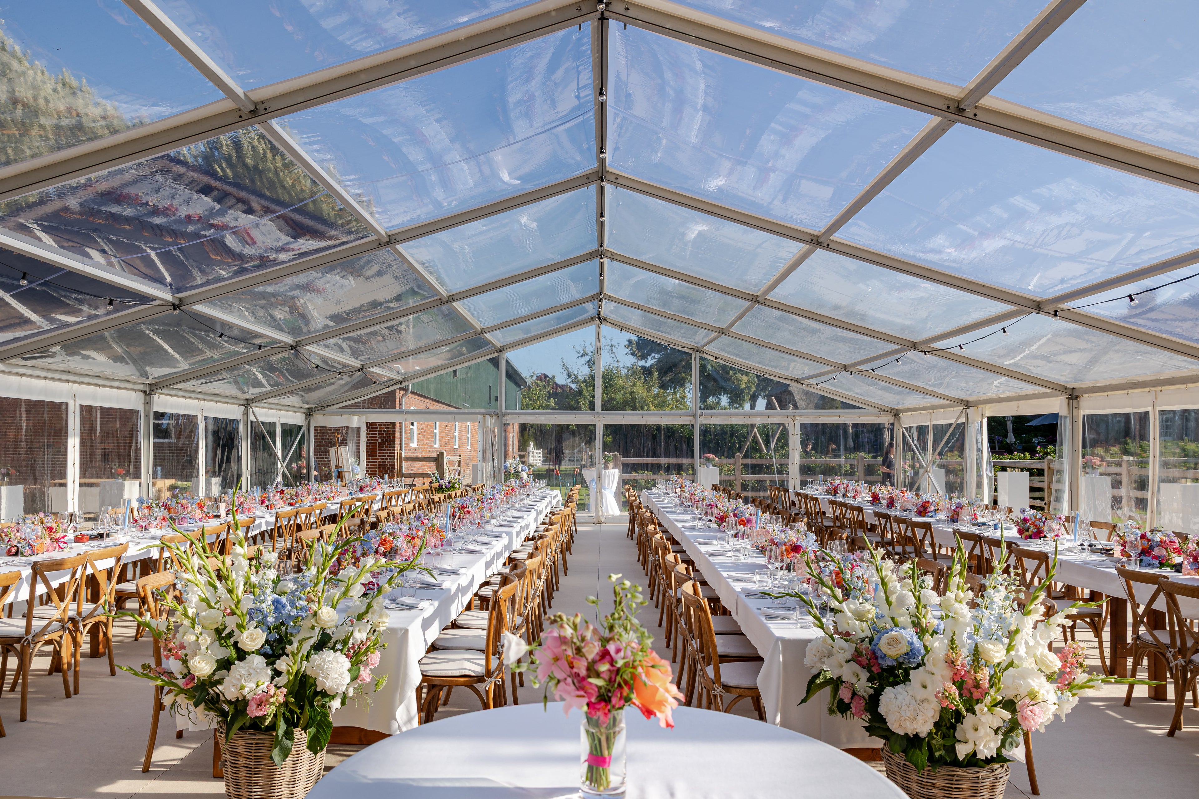 Festzelt mit langen Banketttischen, Holzstühlen, Tischwäsche und Geschirr für eine Hochzeit – Eventausstattung vom Eventverleih Schleswig-Holstein