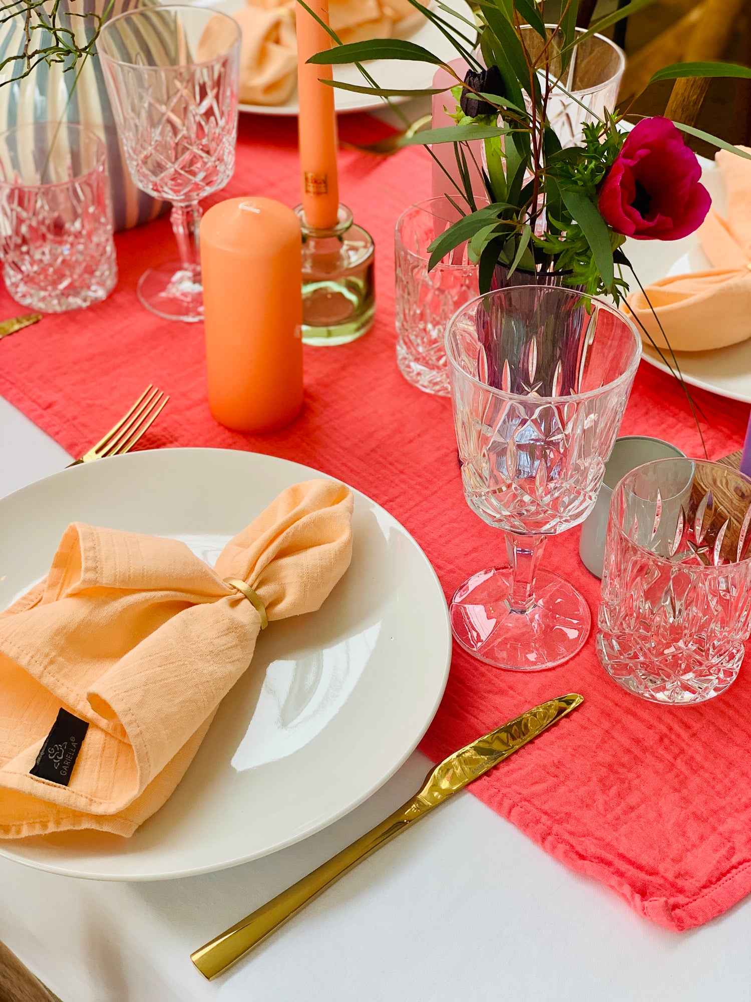 Festlich eingedeckter Hochzeitstisch mit weißem Porzellan, goldfarbenem Besteck, Stoffserviette und Kristallgläsern als stilvolle Tischdekoration für Events